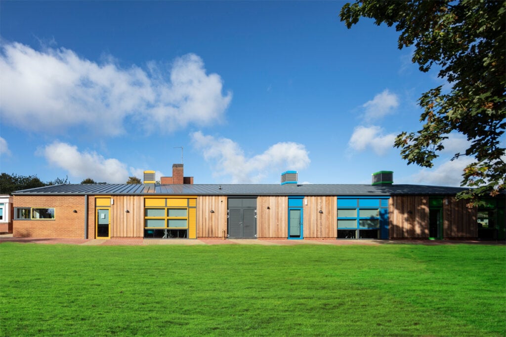 William Morris Primary, Banbury architect designed primary school extension with timber cladding sunny day yellow and blue feature doors and windows